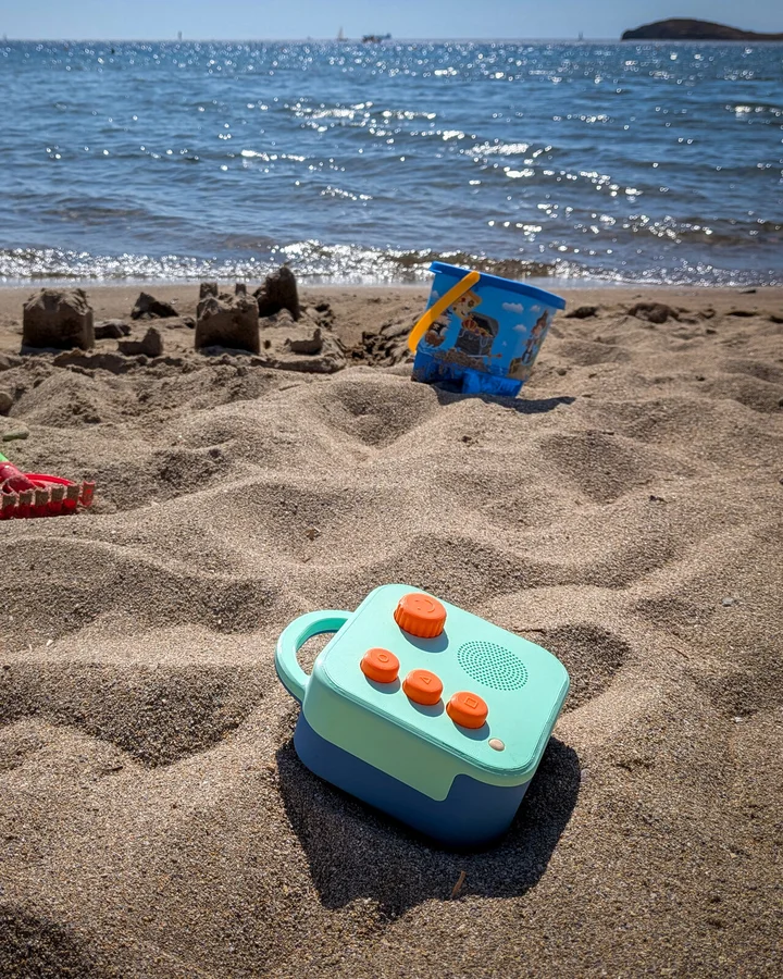 Koobiba audio player on a beach next to sand toys